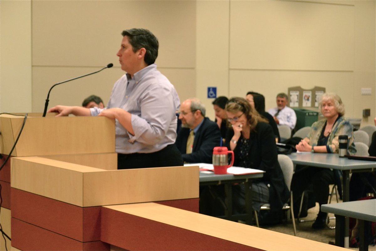 Member of public speaking at a podiun with audience behind
